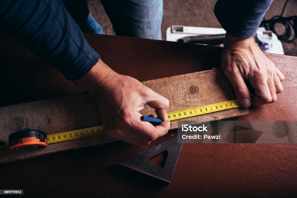 Amateur carpenter measures the board with the meter tape Craft Stock Photo