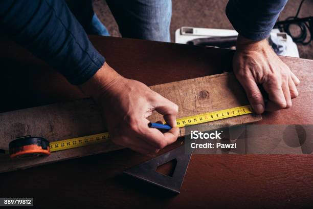 Amateur Carpenter Measures The Board With The Meter Tape Stock Photo - Download Image Now