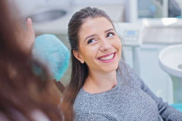 Beautiful woman at dentist office Happy woman having her teeth examined at dentist office. Female dentist performing dental examination on woman. dentists chair stock pictures, royalty-free photos & images