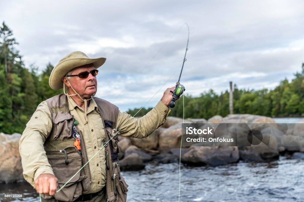 Senior Man Fisherman Fly Fishing in A River Senior Man Fisherman Fly Fishing in A River in summer season in Jacques-Cartier River, Quebec, Canada 65-69 Years Stock Photo