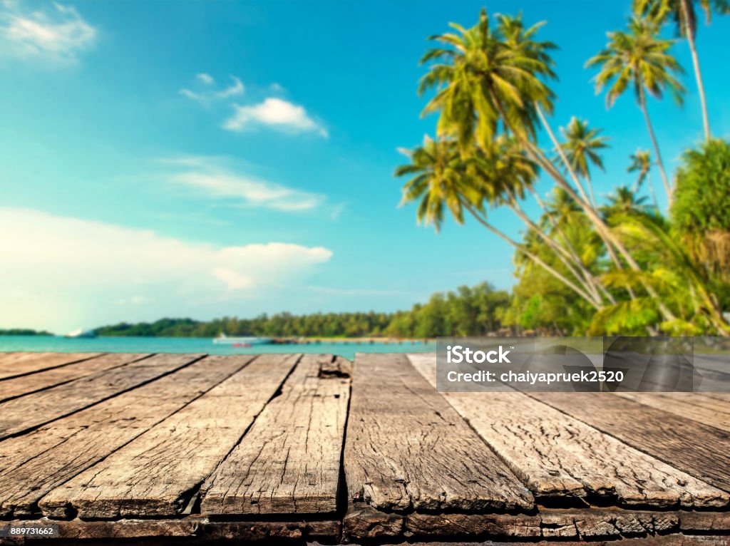 Wood table with blurred sea and coconut tree background Beach Stock Photo