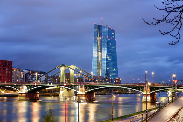 blick auf die beleuchtete skyline frankfurt am main mit flossen brücke und europäische zentralbank in der abenddämmerung - hessen deutschland stock-fotos und bilder