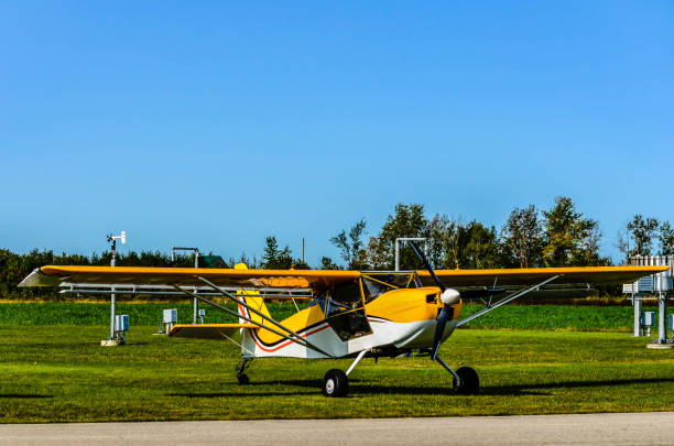 istock front view of a yellow and white single engine airplane parked on the grassnext to a runway with a blue sky background. 889785954
