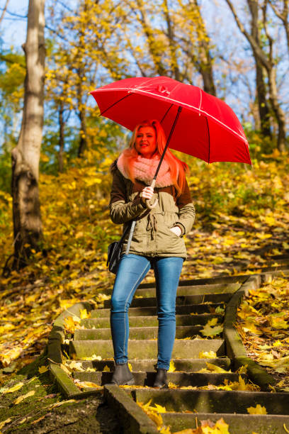 istock Woman walking in park with umbrella 889790732