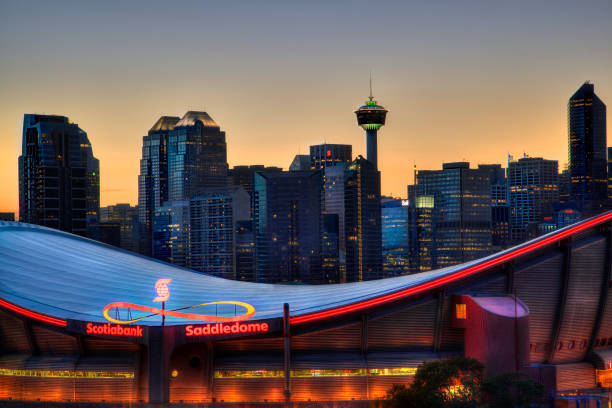 Sunset Over Downtown Calgary and Saddledome Sunset over Calgary's skyline with the Scotiabank Saddledome in the foreground. The dome with its unique saddle shape is home to the Calgary Flames NHL club, and is one of the oldest professional hockey arenas in North America. scotiabank saddledome stock pictures, royalty-free photos & images