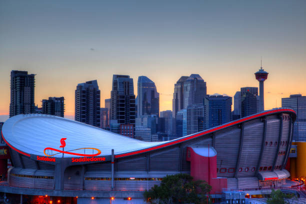 Sunset Over Downtown Calgary and Saddledome Sunset over Calgary's skyline with the Scotiabank Saddledome in the foreground. The dome with its unique saddle shape is home to the Calgary Flames NHL club, and is one of the oldest professional hockey arenas in North America. scotiabank saddledome stock pictures, royalty-free photos & images