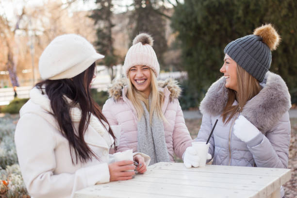 Three young Teenage Girls laughing and drinking hot refreshment