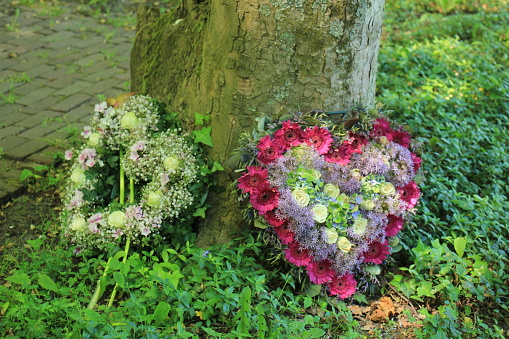 Heart shaped sympathy flowers  or funeral flowers near a tree