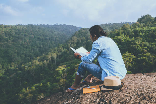 アジア人旅行は休日でリラックスします。席では、岩の崖に本を読むおくつろぎください。山。タイで - writing diary nature ideas ストックフォトと画像