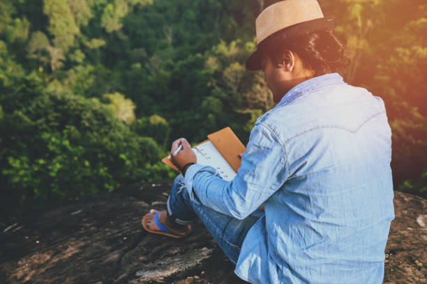 アジア人旅行は休日でリラックスします。席では、岩の崖に本を読むおくつろぎください。山。タイで - writing diary nature ideas ストックフォトと画像