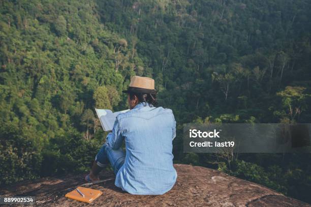 Asian Man Travel Relax In The Holiday Seats Relax Read Books On Rocky Cliffs On The Moutain In Thailand Stock Photo - Download Image Now