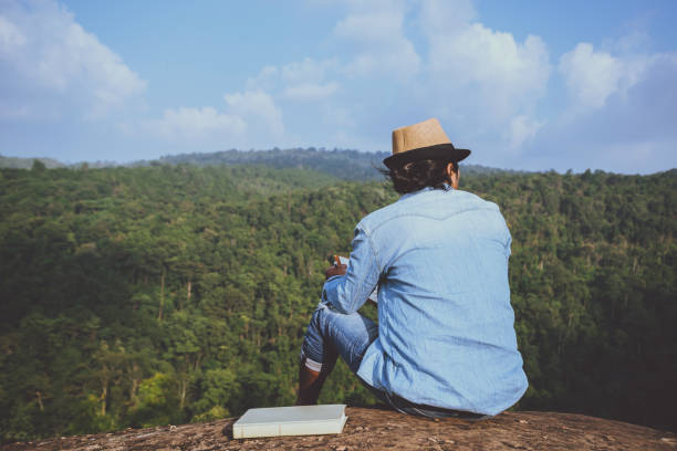 アジア人旅行は休日でリラックスします。席では、岩の崖に本を読むおくつろぎください。山。タイで - writing diary nature ideas ストックフォトと画像