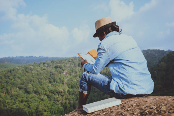 アジア人旅行は休日でリラックスします。席では、岩の崖に本を読む��おくつろぎください。山。タイで - writing diary nature ideas ストックフォトと画像