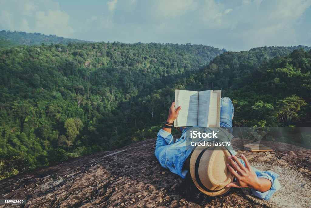 Asian man travel relax in the holiday. sleep relax read books on rocky cliffs. On the Moutain. In Thailand Reading Stock Photo