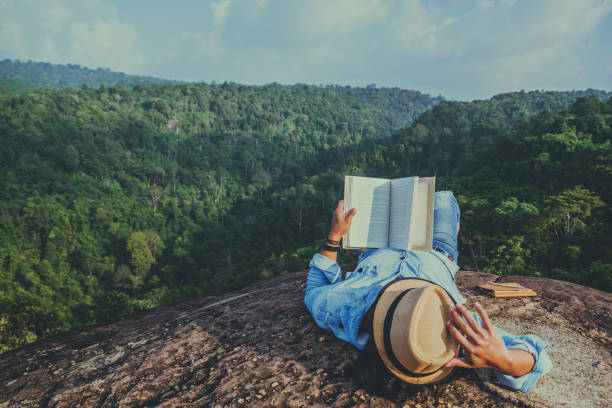 азиатский человек путешествия расслабиться в отпуске. спать расслабиться читать книги на скалистых скалах. на мутене. в таиланде - men reading outdoors book стоковые фото и изображения