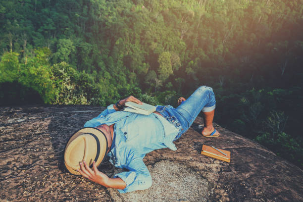 アジア人旅行は休日でリラックスします。スリープ リラックス岩の崖に本を読む。山。タイで - writing diary nature ideas ストックフォトと画像