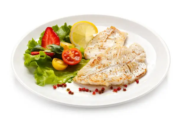 Fish dish - fried fish fillet and vegetables on white background
