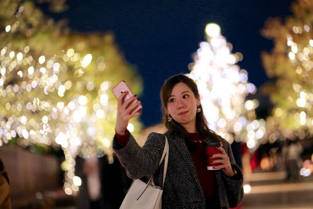 istock Young woman trying selfie before Christmas lights 889928164