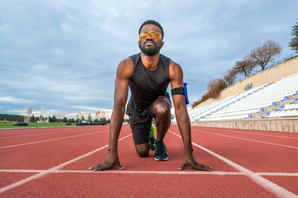 atleta maschile alla linea di partenza pronto a iniziare la gara - rivalry starting block track and field athlete track and field foto e immagini stock