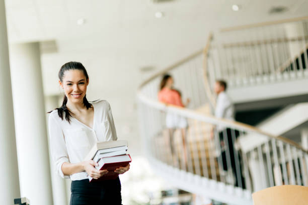 istock Beautiful woman holding books in a library 889976662