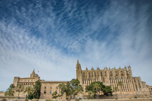 Palma Cathedral, the Almudaina Palace and sea wall fortifications of Palma Palma de Mallorca, Spain - April 11, 2016: the historic core of Palma de Mallorca, the largest city on the island of Mallorca.  The cathedral (right hand side of image), La Seu, was built between 1229 and 1601 on the site of a muslim mosque (which Juame I's military forces destroyed when they took control of the island from the Moors in 1229).  The cathedral is Gothic in style.  The royal palace (left-hand side of the cathedral) is the Royal Palace of La Almudaina.  It was constructed before the cathedral by the Moors as a fort, and so retains elements of Islamic architecture, blended with the Gothic styling of later Christian additions. ethnic cleansing stock pictures, royalty-free photos & images