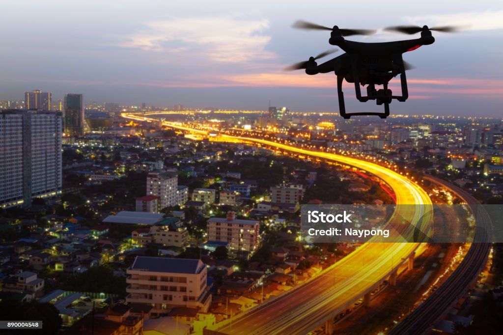 Silhouette of drone flying above city at sunset Drone Stock Photo