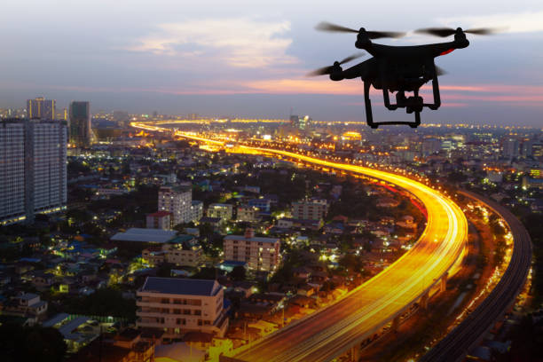 Silhouette of drone flying above city at sunset Silhouette of drone flying above city at sunset mid air photos stock pictures, royalty-free photos & images