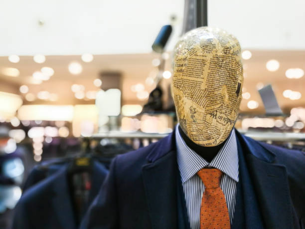 Mannequin with head wrapped in newspaper article modeling smart suit, shirt and tie in department store