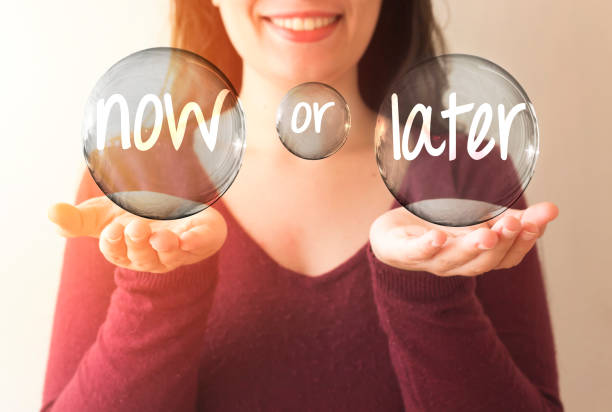 istock business woman holding transparent bubble with now or later text 890080894
