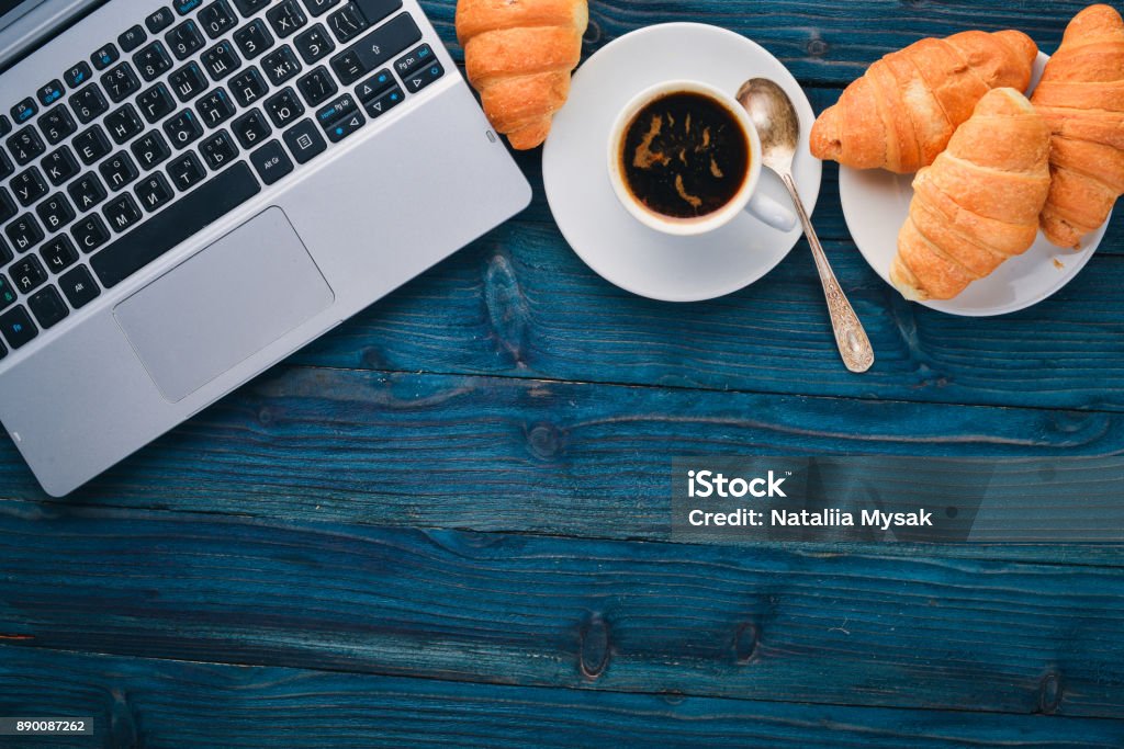 Business breakfast, coffee and croissants, on a wooden surface. Top view. Free space for text. Breakfast Stock Photo