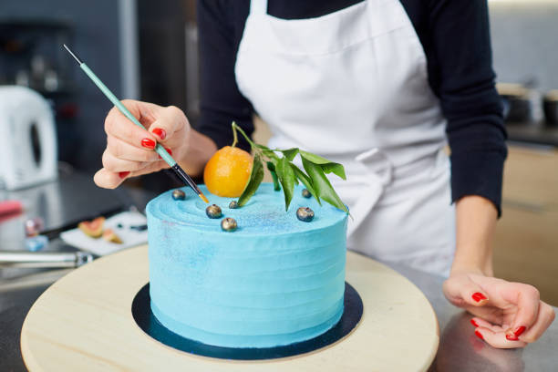 The confectioner decorates the cake on the table in the kitchen.