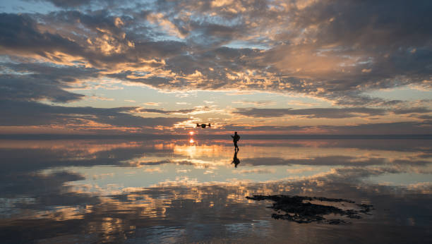 istock Photographer  having fun with Drone on salt lake at sunset 890105050