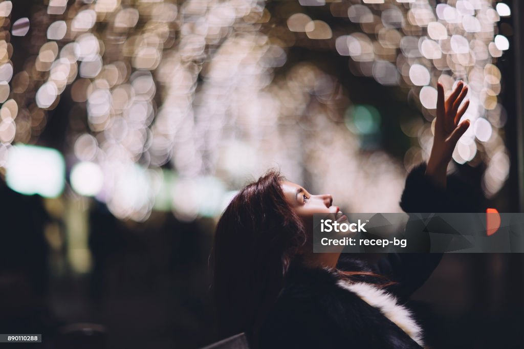 Woman Trying To Reach Light A Japanese young woman is extending her arm to reach light at night. New Year Stock Photo