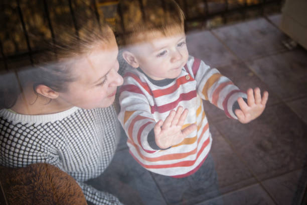 istock Mother with her little son looking out of window 890120752