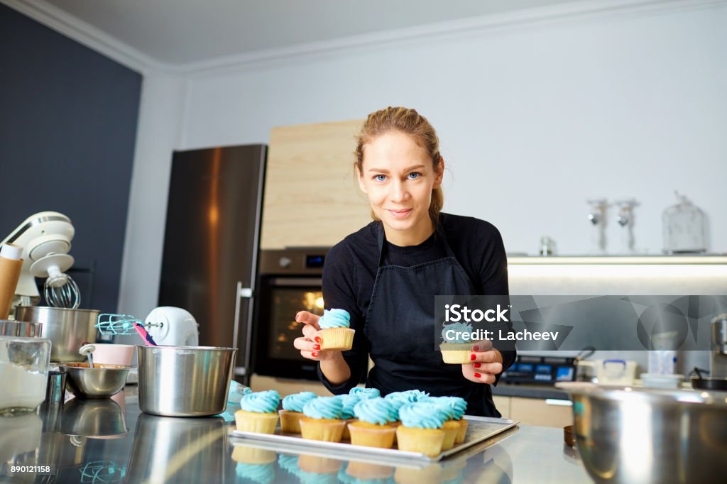 Femme de pâtissier confiseur tenant un plateau de petits gâteaux. - Photo de Décorer un gâteau libre de droits