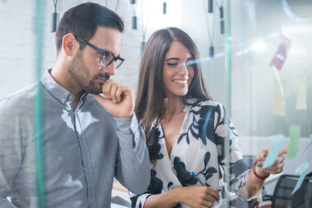 istock Team of focused colleagues discussing ideas and brainstorming with sticky notes on glass wall. 890136134