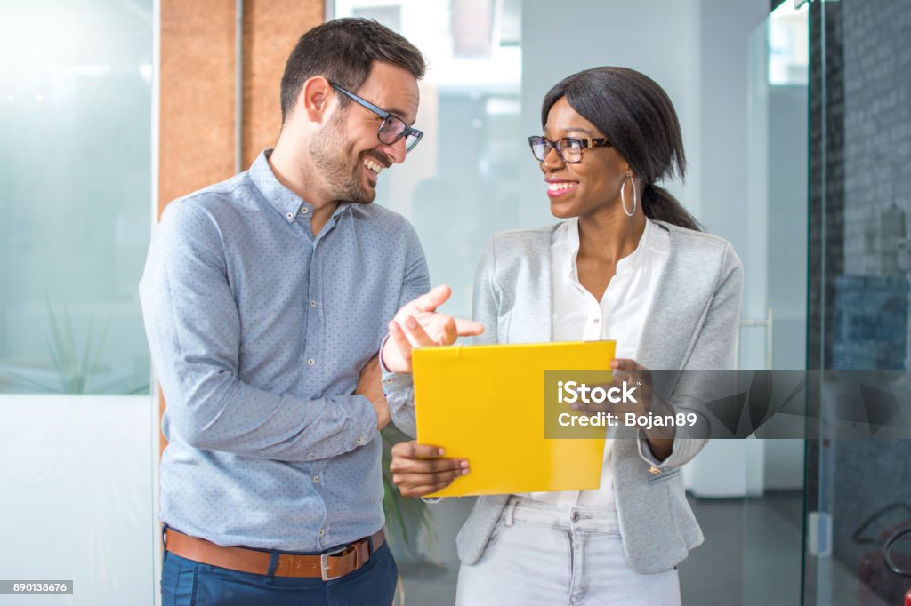 Smiling business partners commenting contract while walking in office hall. Discussion Stock Photo