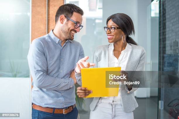 Smiling Business Partners Commenting Contract While Walking In Office Hall Stock Photo - Download Image Now