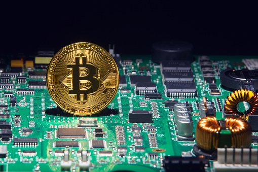 Sao Paulo, Brazil - December 08, 2017: Gold Bitcoin virtual currency on a circuit board background