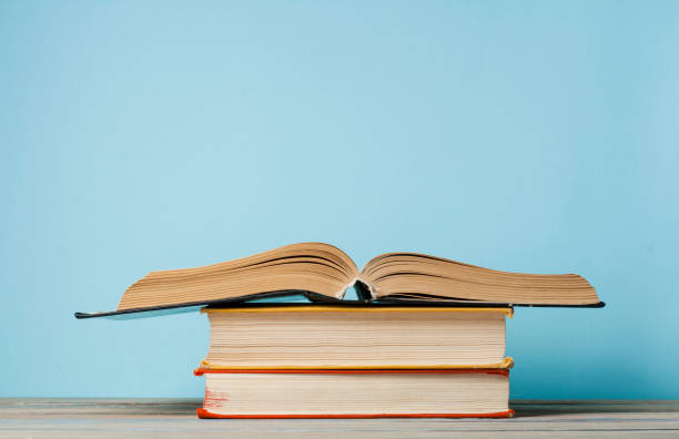 istock Open book, hardback books on wooden table and blue wall .Education background. Back to school. Copy space for text. 890154972