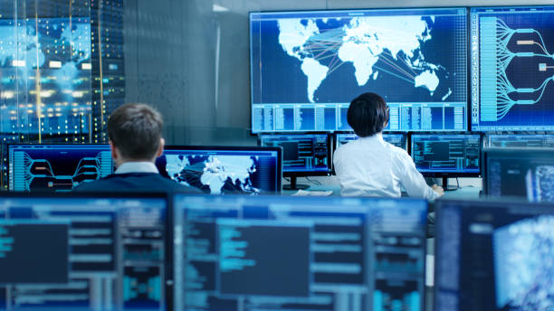 In the System Control Room Operator and Administrator Sitting at Their Workstations with Multiple Displays Showing Graphics and Logistics Information. In the System Control Room Operator and Administrator Sitting at Their Workstations with Multiple Displays Showing Graphics and Logistics Information. facilities protection services stock pictures, royalty-free photos & images