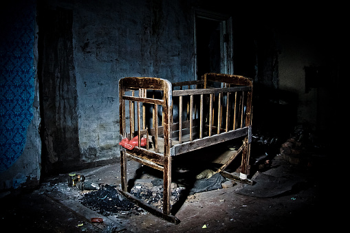 Old creepy eerie wooden baby crib in abandoned house. Horror concept.