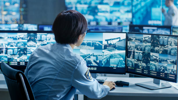 In the Security Control Room Officer Monitors Multiple Screens for Suspicious Activities. He's Surrounded by Monitors and Guards Facility of National Importance. In the Security Control Room Officer Monitors Multiple Screens for Suspicious Activities. He's Surrounded by Monitors and Guards Facility of National Importance. terminal tower stock pictures, royalty-free photos & images