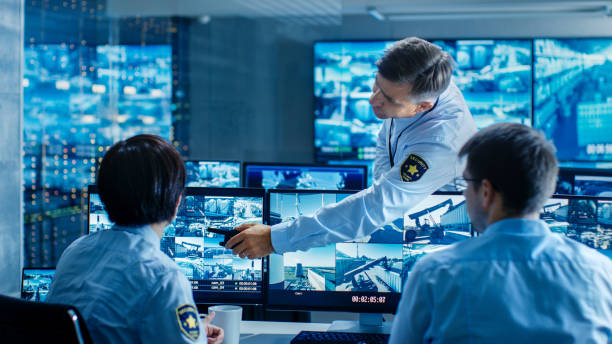 In the Security Control Room Chief Surveillance Officer Showing on Screen a Crime for Two of His Subordinates. Multiple Screens Show that They Guard Object of International Importance. In the Security Control Room Chief Surveillance Officer Showing on Screen a Crime for Two of His Subordinates. Multiple Screens Show that They Guard Object of International Importance. terminal tower stock pictures, royalty-free photos & images