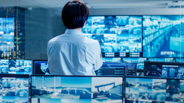 In the Security Control Room Officer Monitors Multiple Screens for Suspicious Activities. He Guards Internationally Important Logistics Facility. In the Security Control Room Officer Monitors Multiple Screens for Suspicious Activities. He Guards Internationally Important Logistics Facility. terminal tower stock pictures, royalty-free photos & images