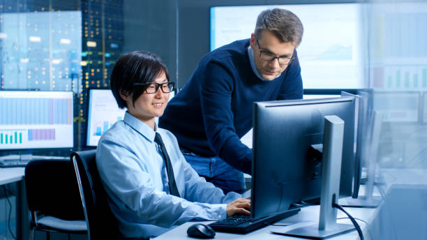 istock In the Data Mining Center Chief Statistician Consults His Young Assistant sits at His Workstation Surrounded with Monitors Displaying Data and Graphs. 890157322