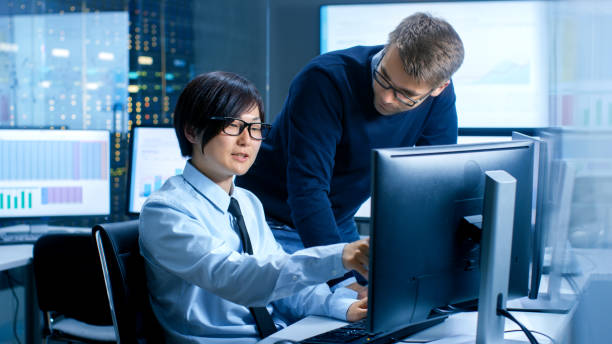 istock In the Data Mining Center Chief Statistician Consults His Young Assistant sits at His Workstation Surrounded with Monitors Displaying Data and Graphs. 890157324