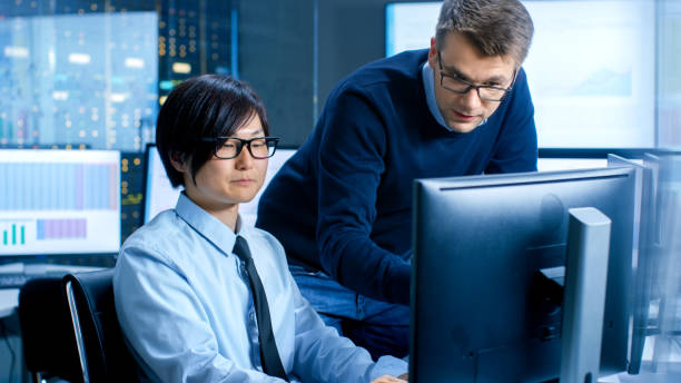 istock In the Data Mining Center Chief Statistician Consults His Young Assistant sits at His Workstation Surrounded with Monitors Displaying Data and Graphs. 890157332