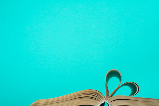 Heart from book page on blue background. Education concept. Close up heart shape from paper book on blue background. Copy space for text. book heart shape valentines day copy space stock pictures, royalty-free photos & images