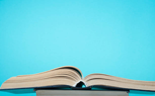 istock Open book, hardback books and blue wall. Education background. Back to school. Copy space for text. 890160362